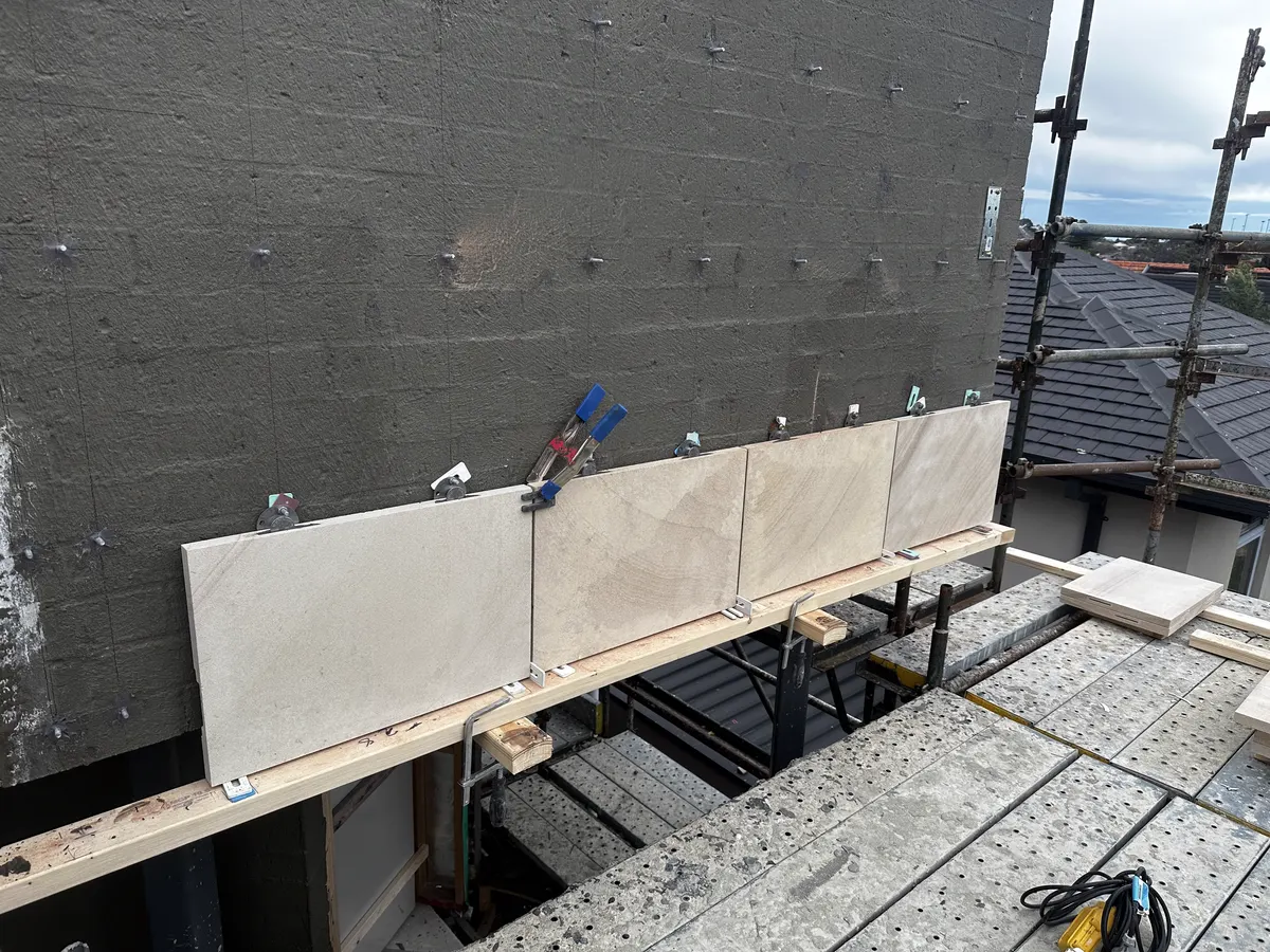 Stone panels clamped in place on mechanical fixing brackets during facade installation