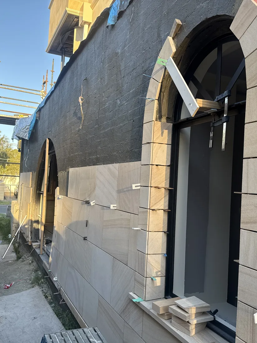 Sandstone panel installation around an arched doorway opening