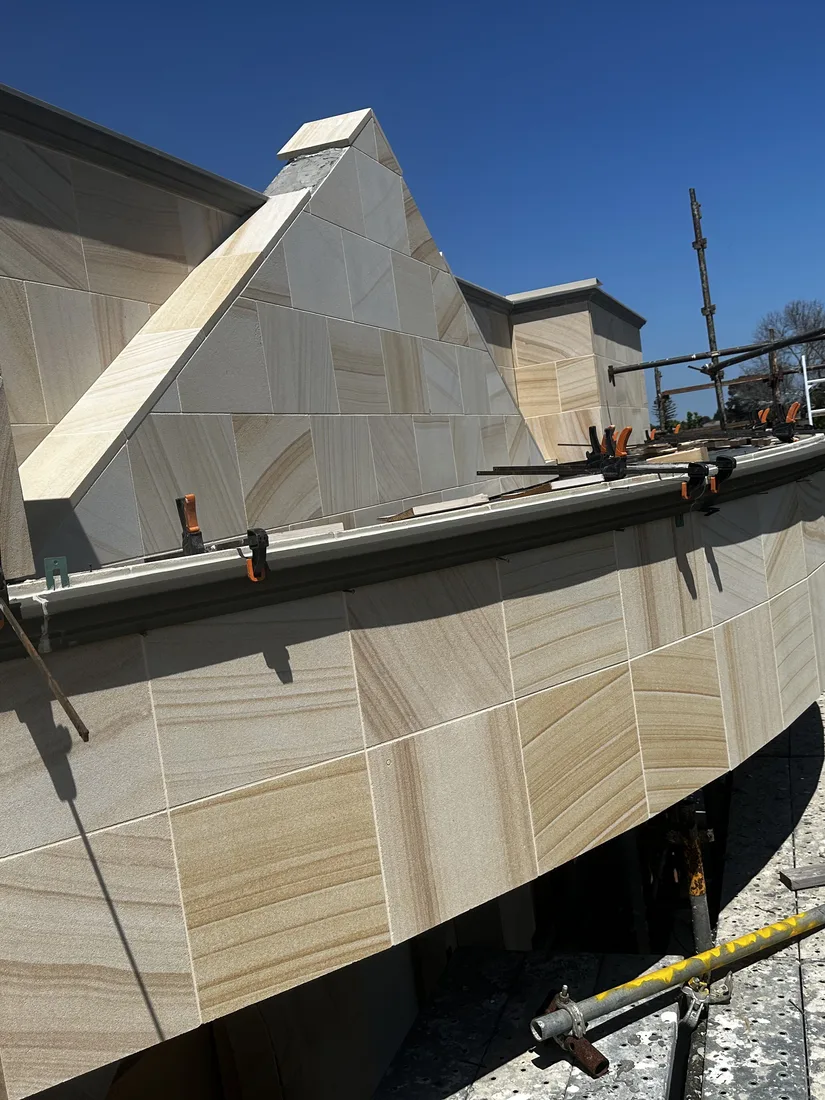Sandstone cladding to the curved parapet and cornice detail