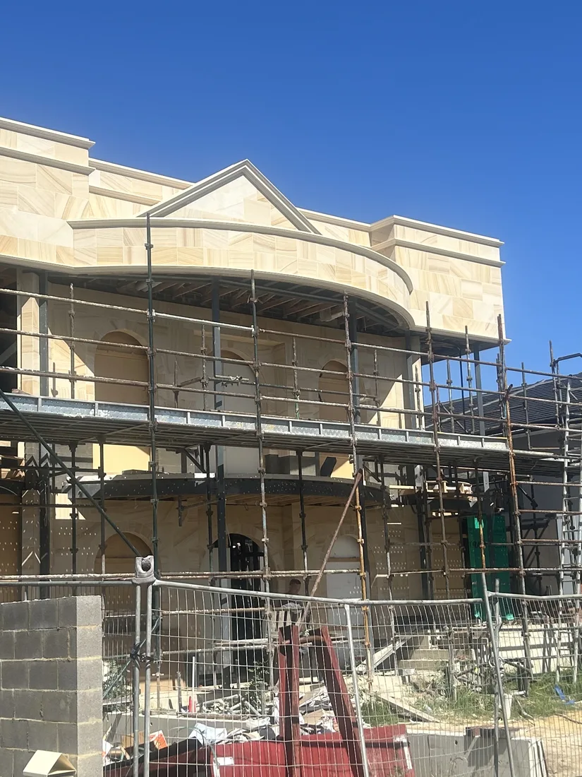 Progress view of the sandstone façade with a curved bay window