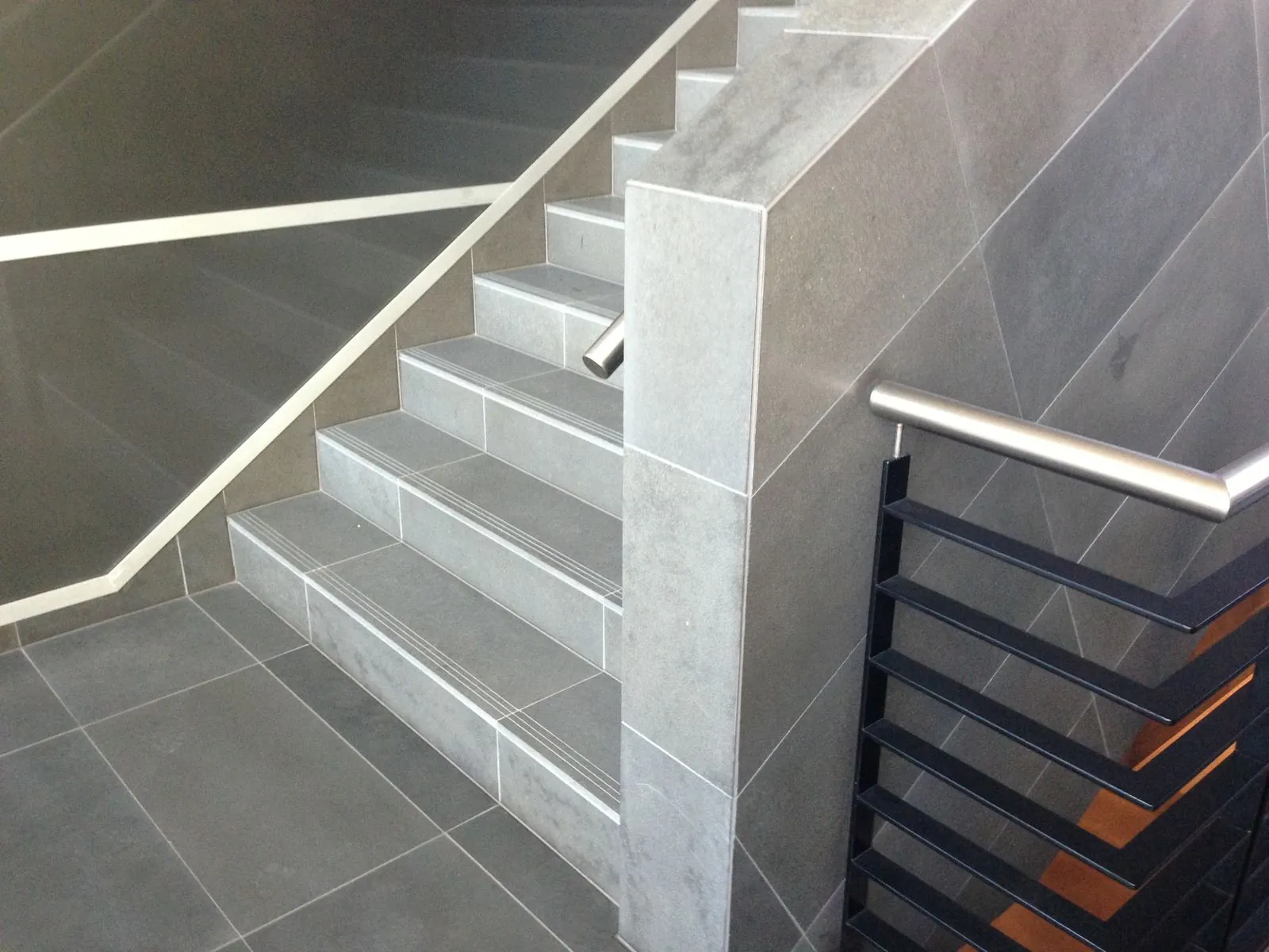Granite wall cladding installed along an interior corridor with bathroom entrances