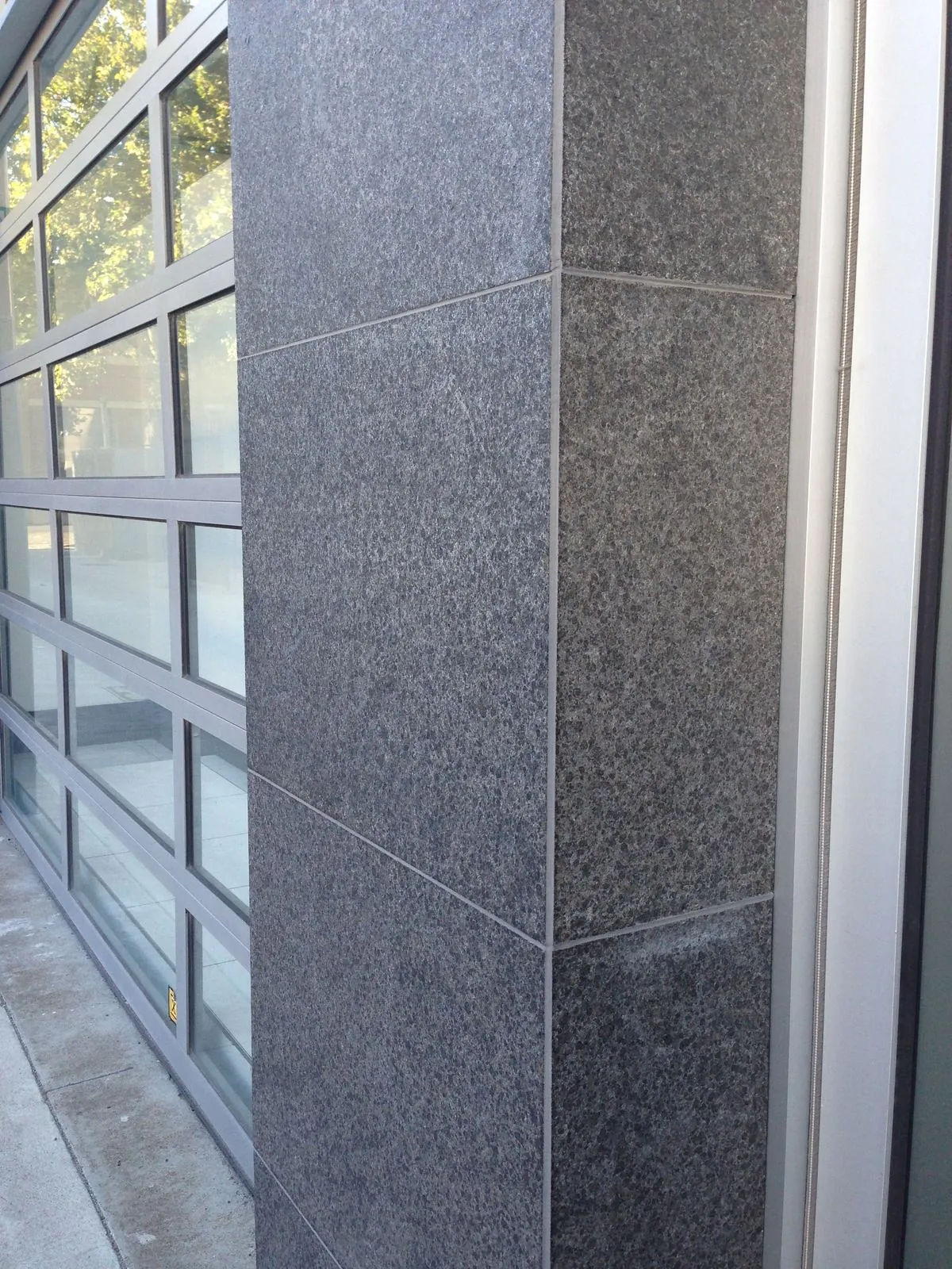 Close-up detail of mechanically fixed flamed granite panel joints on the building exterior