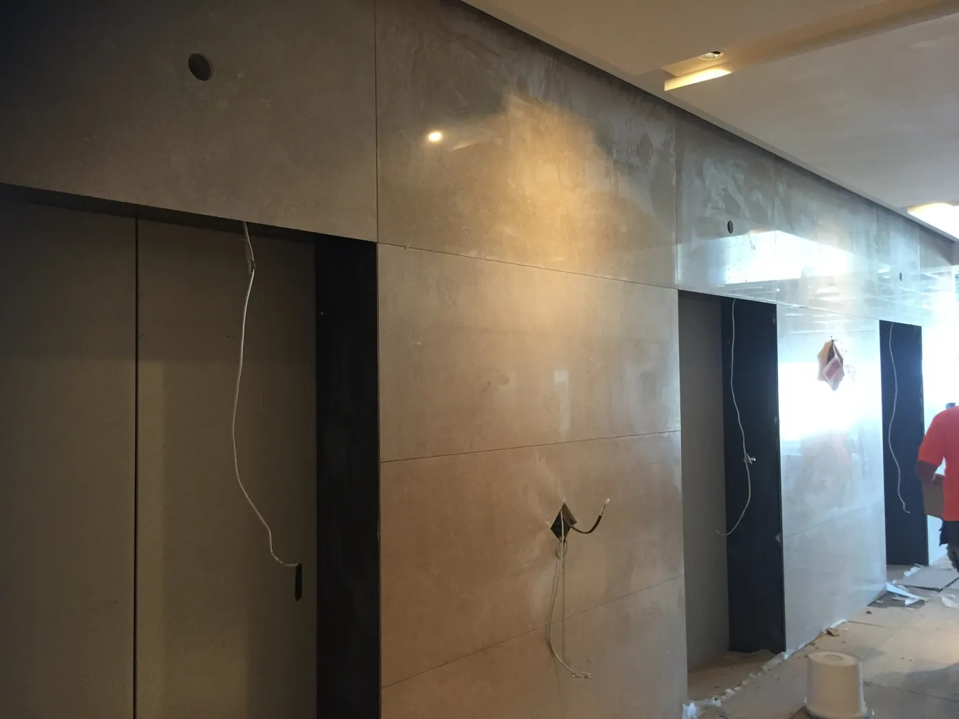 Crema Marfil marble lift lobby wall panels installed with black granite reveals
