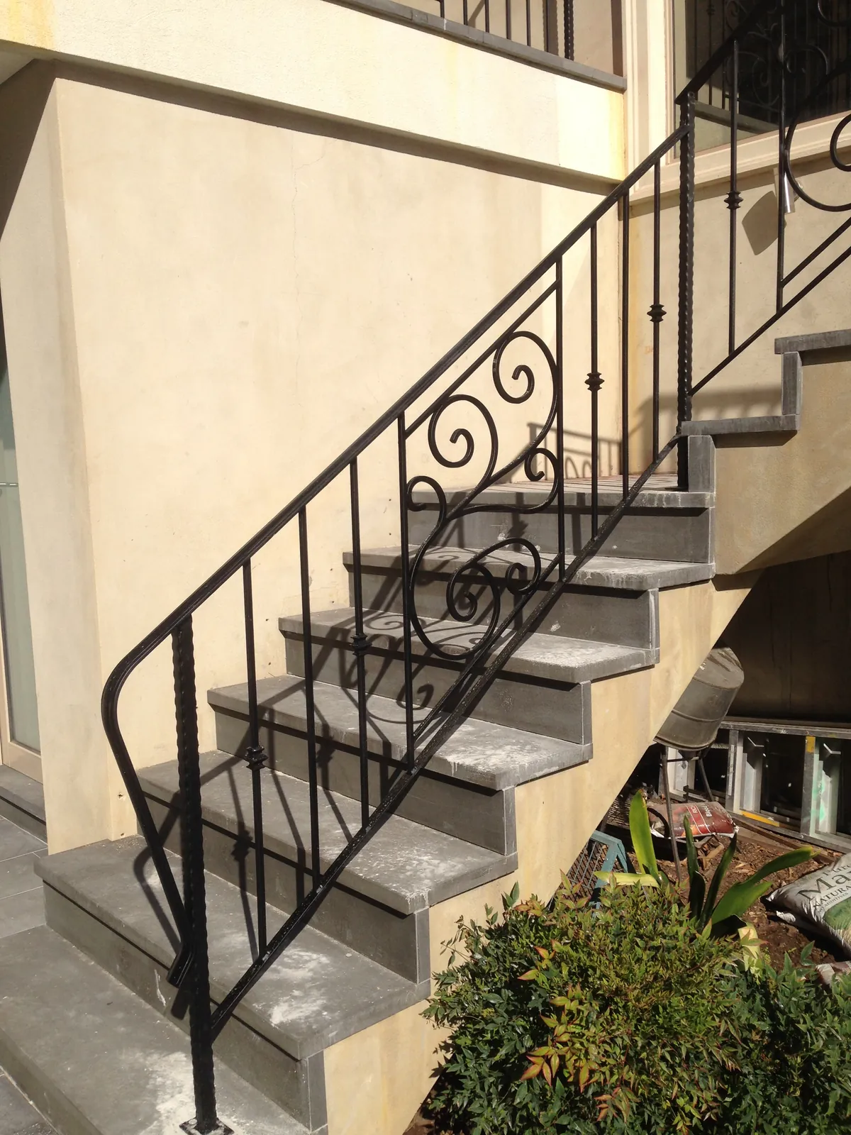 Bluestone stair treads installed on an exterior staircase with wrought iron balustrade