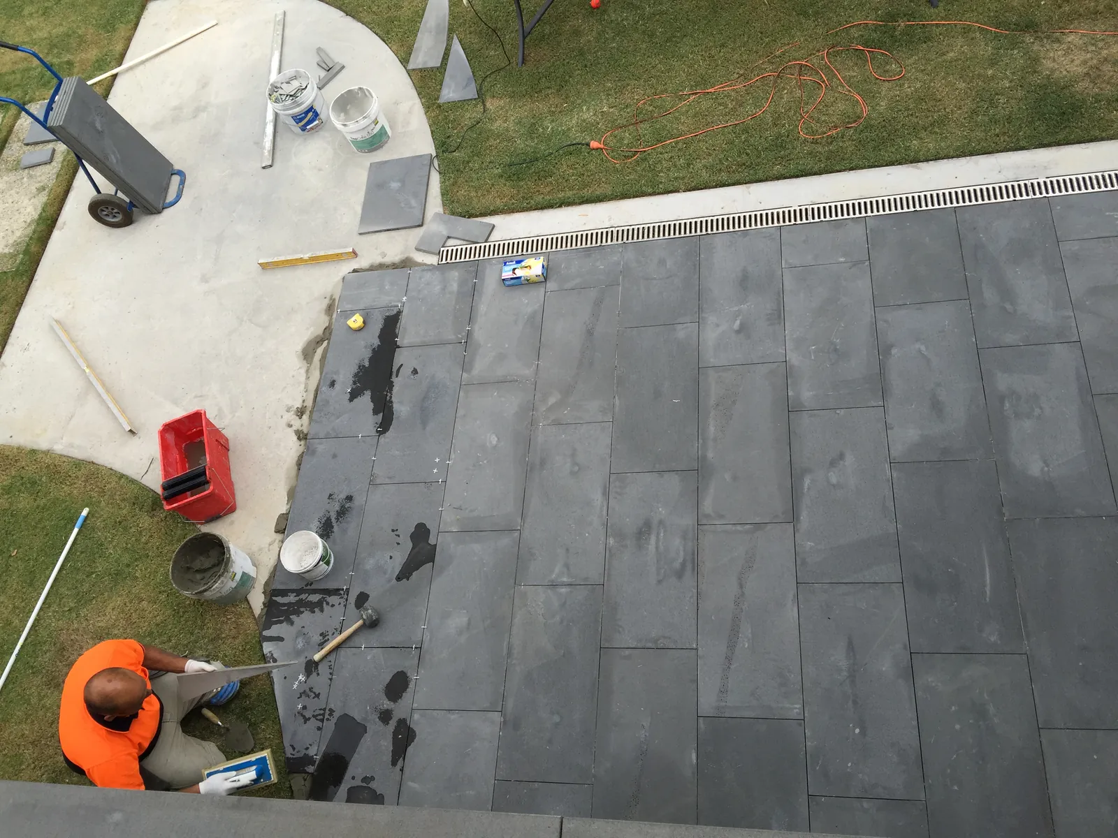 Tradesman laying bluestone pavers around a circular garden bed on the rear patio