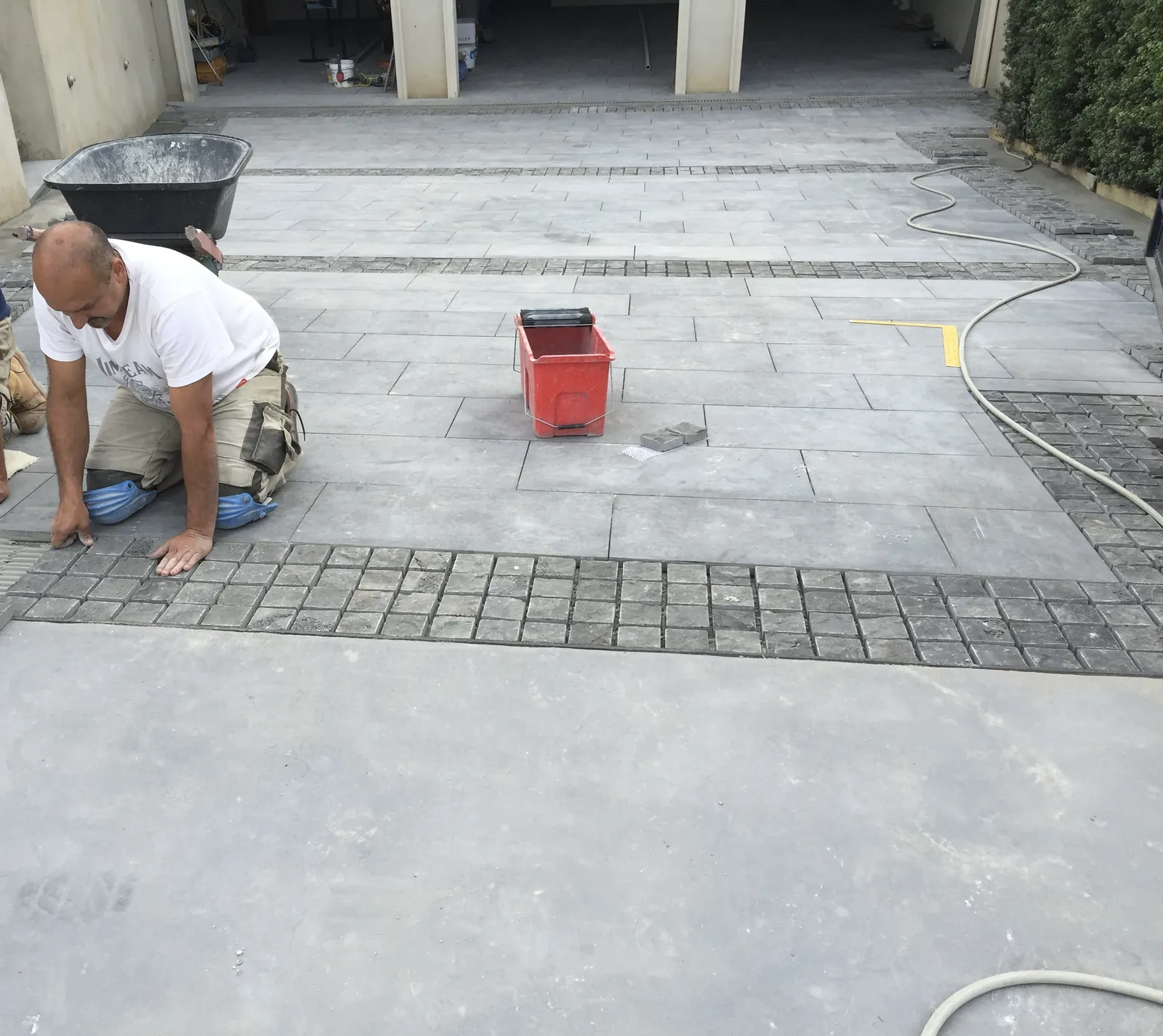 Tradesman laying the cobblestone border edge of the bluestone driveway