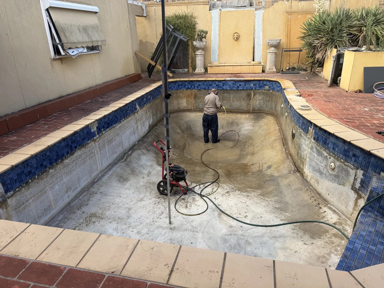 Pressure washing the pool shell to prepare for waterproofing