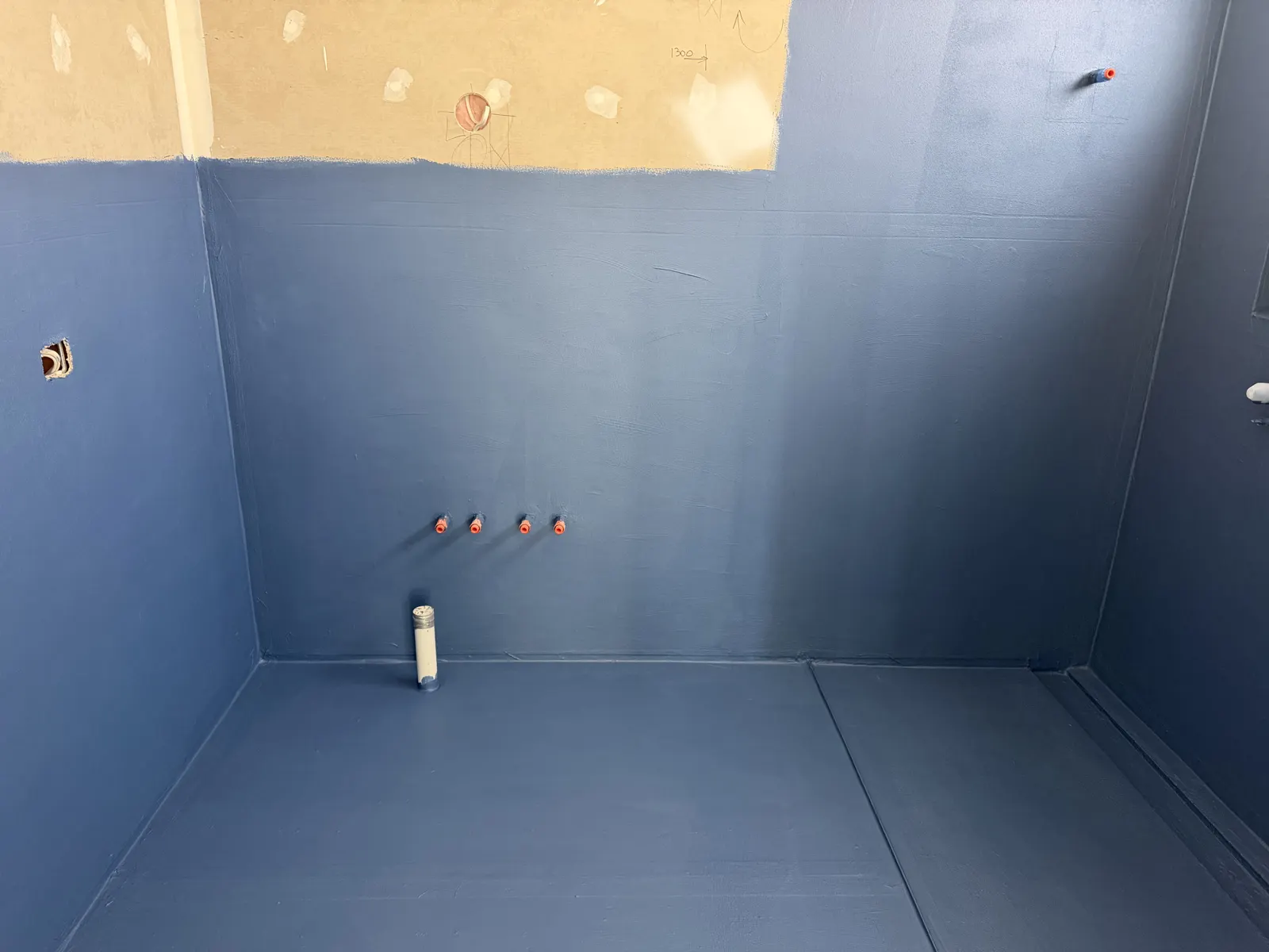 Waterproofing membrane sealed around pipe penetrations in bathroom floor
